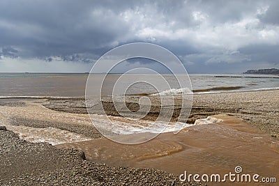 The beach of BenicÃ ssim-BenicÃ¡sim and the Mediterranean Sea joining with rainwater and floods producing a mixture of sediments l Stock Photo